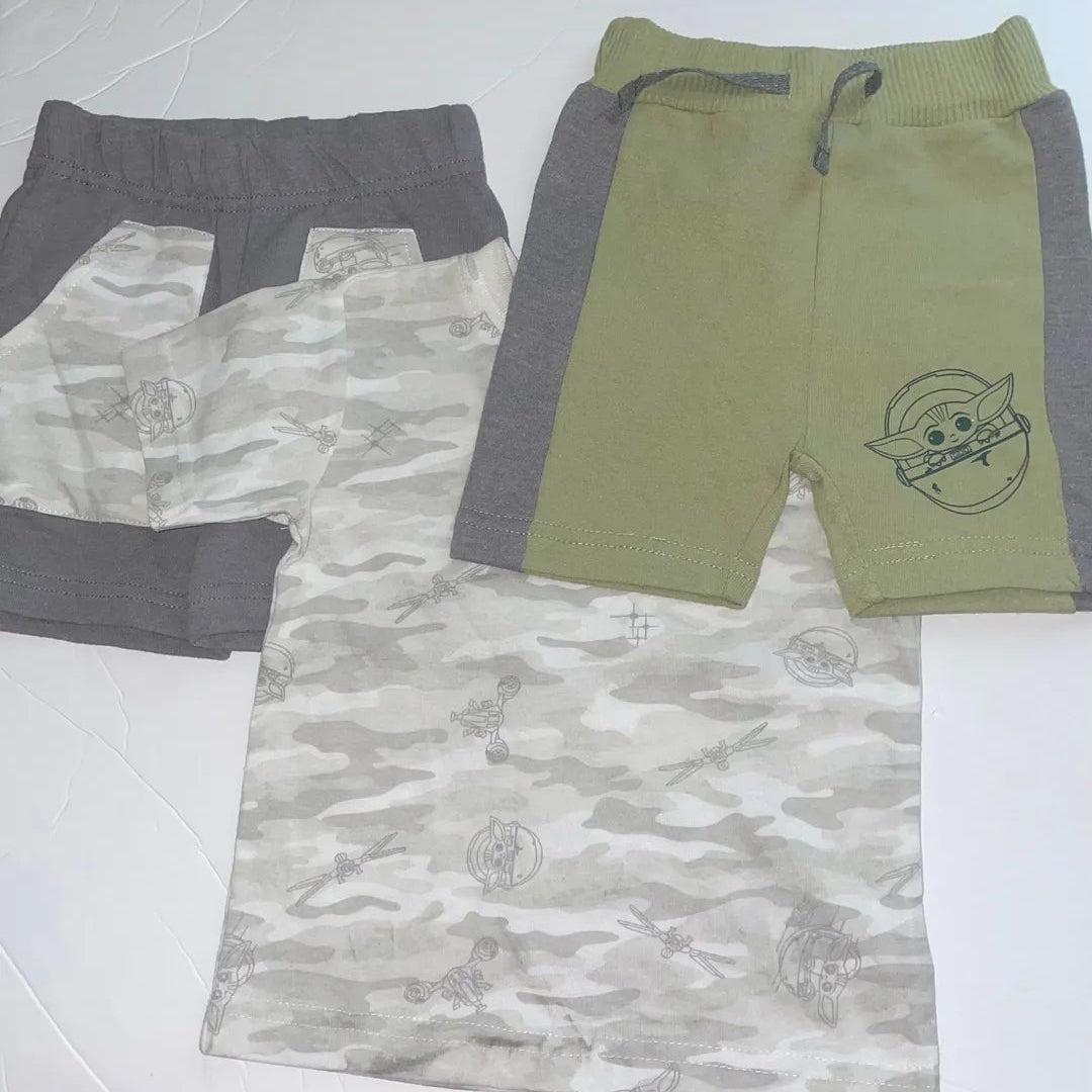 Two pairs of shorts, one camouflage and one green with a graphic design, on a white background.