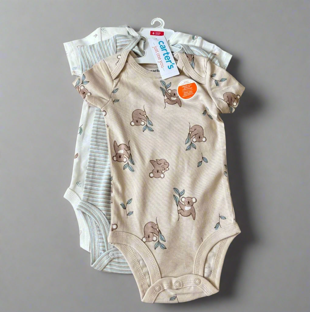 Baby onesie with bear pattern on a wooden surface, featuring a Carter's tag.